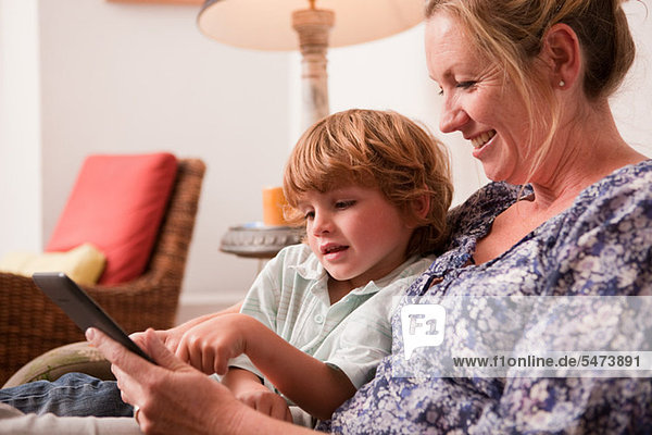 Son using a digital tablet with his mother