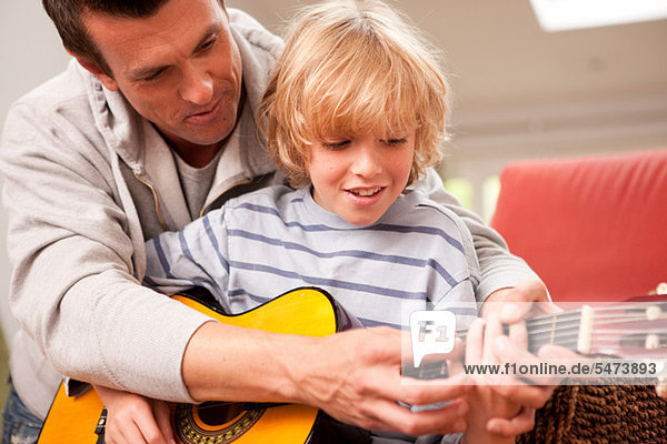 Father showing his son how to play a guitar