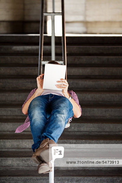 Ein junger Mann auf dem Rücken liegend eines digitalen Tabletts