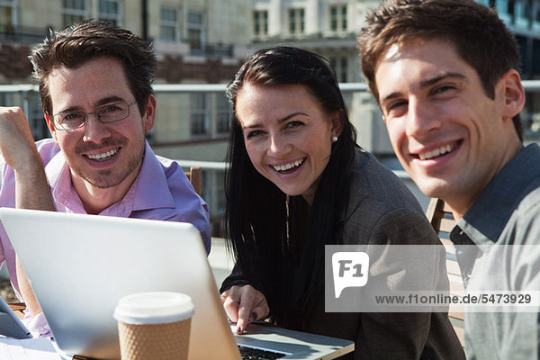 Drei Menschen Lächeln in die Kamera beim benutze ein laptop