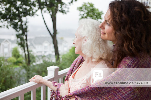 Seniorin und Tochter umarmen sich auf der Veranda