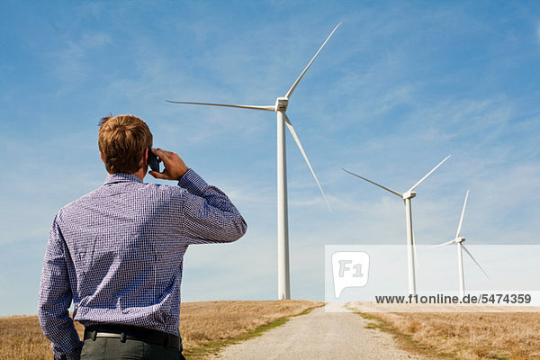Man on mobile phone watching wind turbines