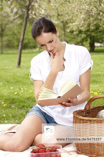 Junge Frau liest ein Buch auf der Wiese