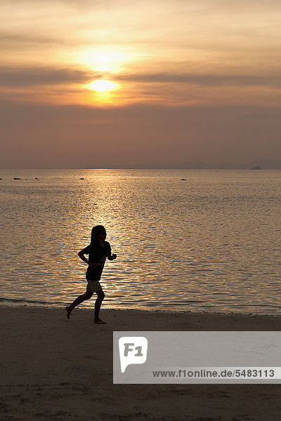 Frau joggt am Strand bei Sonnenuntergang  Hat Tham Phra Nang Strand  Krabi  Thailand  Asien