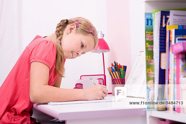 Junge Schülerin bei ihren Hausaufgaben am Schreibtisch
