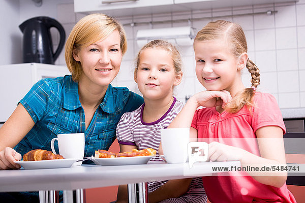 Mutter mit zwei Töchtern beim Frühstück in der Küche