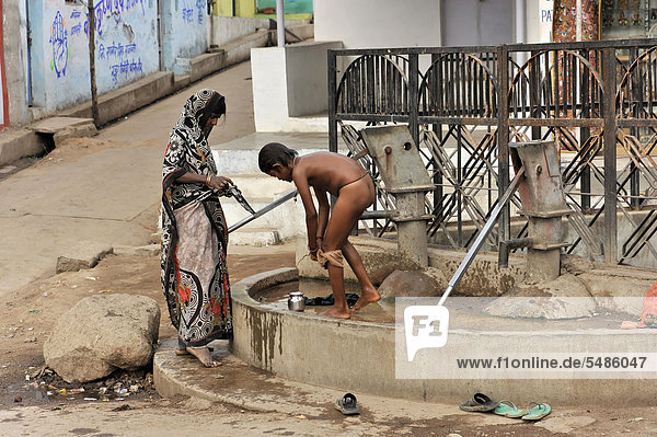Indische Mutter wäscht Ihren Sohn am Dorfbrunnen  Orchha  Madhya Pradesh  Nordindien  Indien  Asien