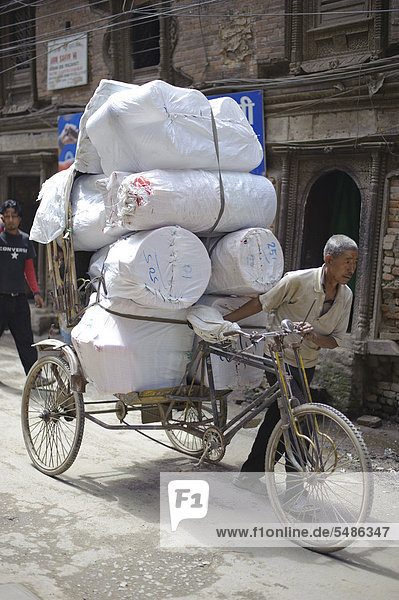 Man with a heavily-laden bicycle on a street in Kathmandu  Bagmati  Nepal  South Asia  Asia