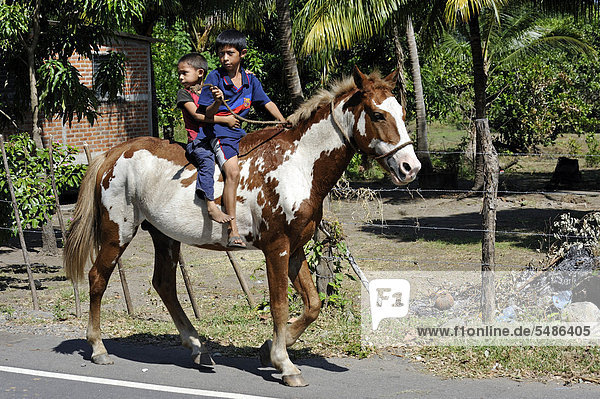 Two boys riding on horseback  El Angel  Bajo Lempa  El Salvador  Central America  Latin America