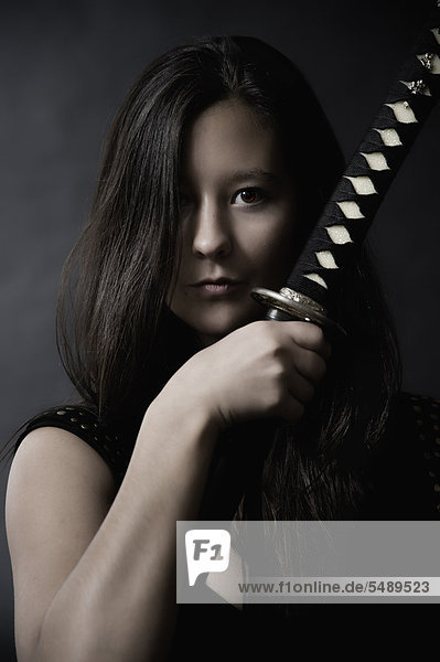 Junge Frau mit Schwert auf schwarzem Hintergrund  Portrait
