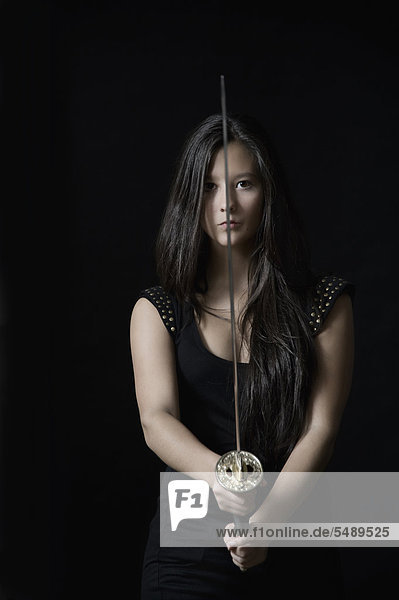 Young woman with sword against black background  portrait