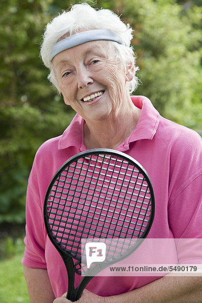Senior woman holding badminton racket  smiling  portrait
