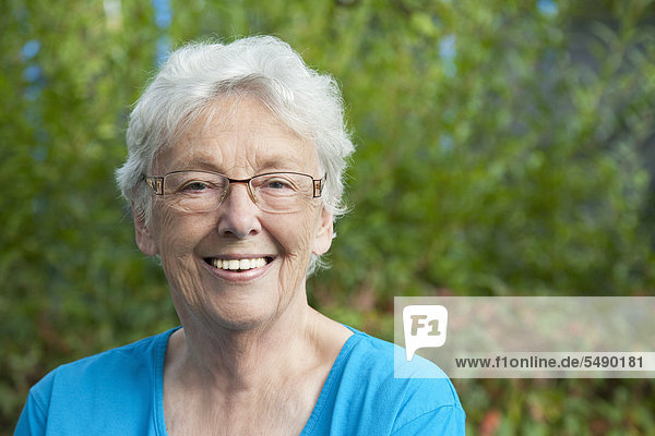 Senior woman in garden  smiling  portrait