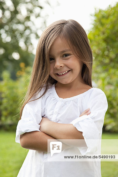 Girl with arms crossed in garden  smiling  portrait