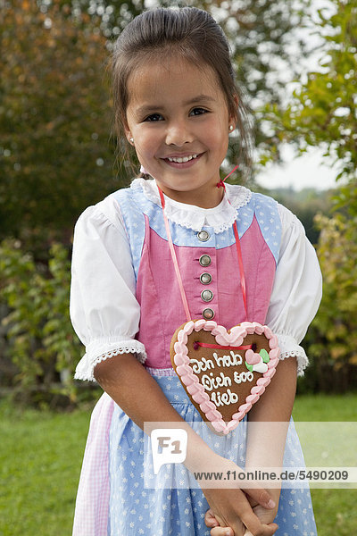 Girl with gingerbread heart in garden  smiling  portrait