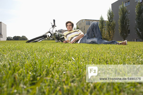 Junger Mann im Gras liegend