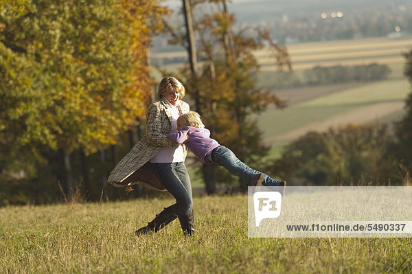 Deutschland  Bayern  Mutter und Tochter spielen im Herbst auf der Wiese