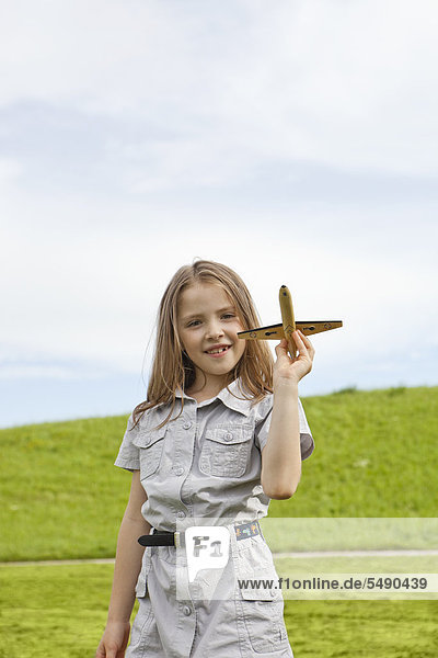Mädchen spielt mit Modellflugzeug im Park,  lächelnd,  Porträt