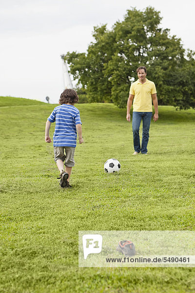 Deutschland  Bayern  Vater und Sohn spielen Fußball im Park