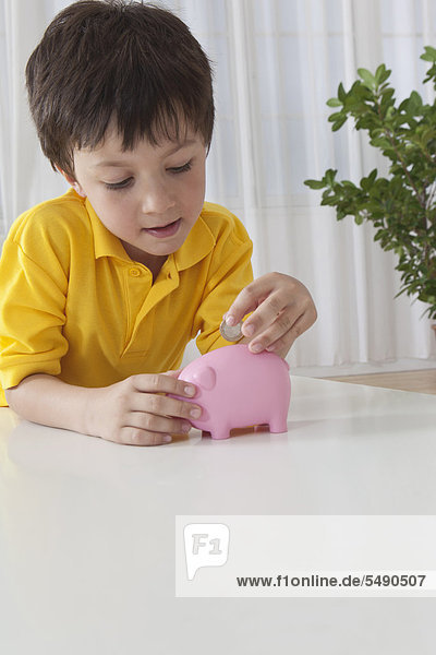 Boy putting money in piggy bank