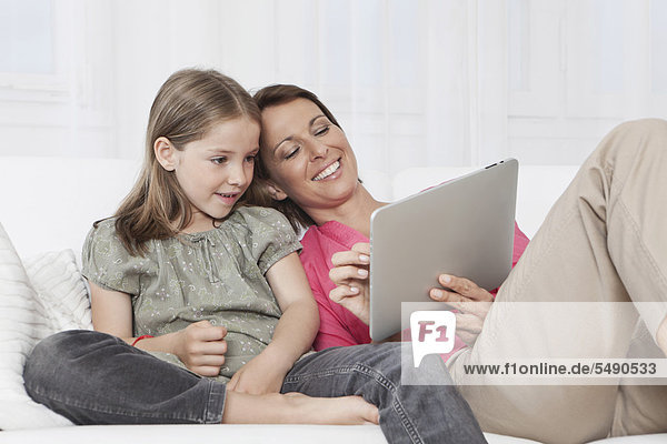 Germany  Munich  Mother and daughter using digital tablet  smiling