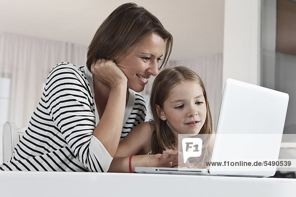 Germany  Munich  Mother and daughter using laptop  smiling