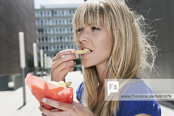 Junge Frau isst Pommes frites