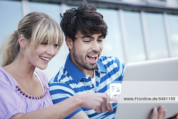 Germany  Cologne  Young couple using laptop  smiling