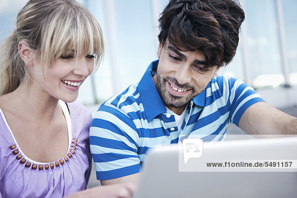 Deutschland  Köln  Junges Paar mit Laptop  lächelnd
