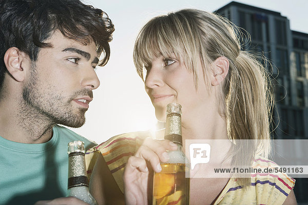 Deutschland  Köln  Junges Paar beim Biertrinken  lächelnd  Nahaufnahme
