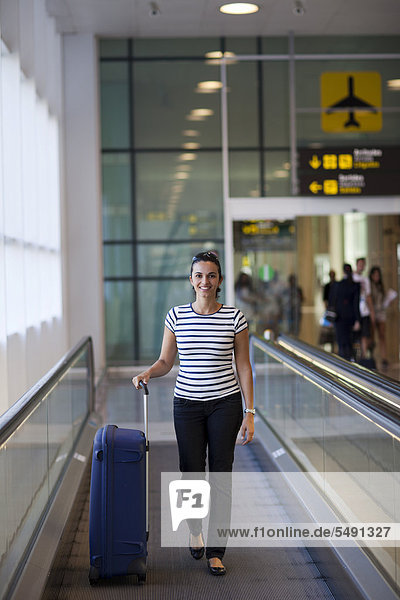 Frau mit Koffer am Flughafen