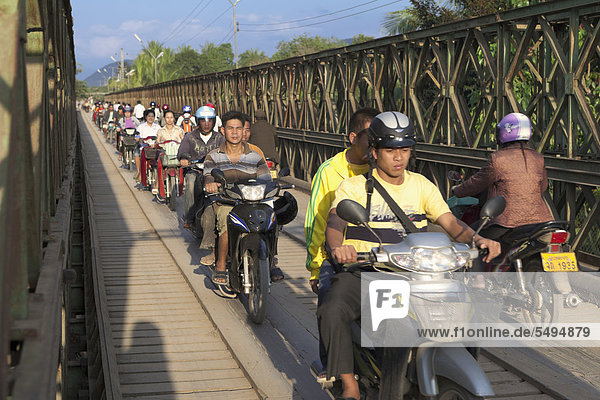 Cyclists on the pedestrian bridge over the Nam Khan River  Luang Prabang  Laos  Southeast Asia