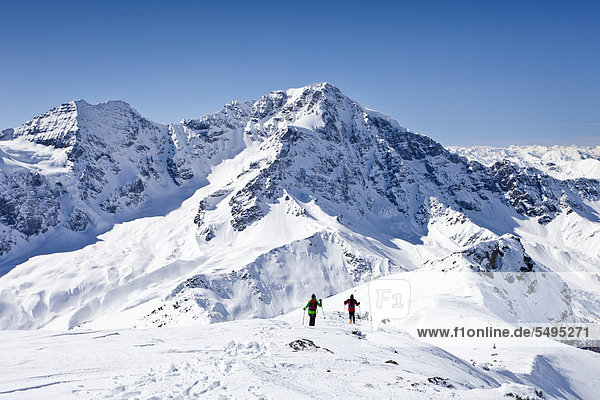 Ski tourers climbing down hintere Schoentaufspitze  Sulden in winter  Zebru mountain and Ortler mountain at the back  province of Bolzano-Bozen  Italy  Europe