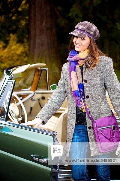 Young woman in front of post-war classic car