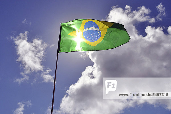 Brazilian national flag against a blue sky with clouds South America