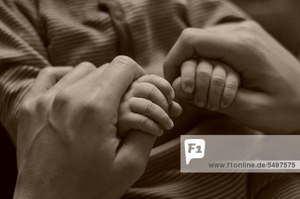 Elternhände umfassen Babyhände