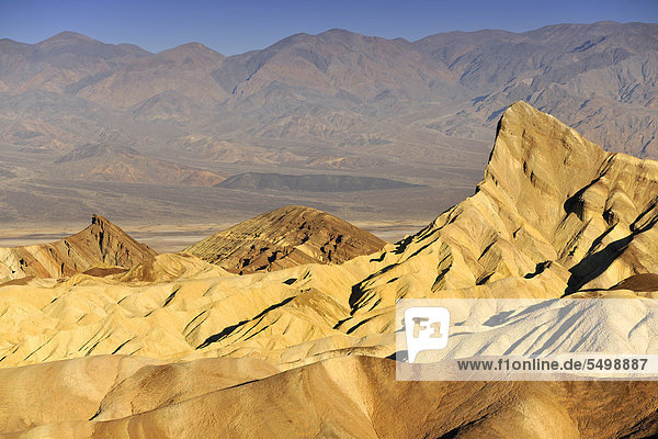 Blick von Zabriskie  auch Zabriske Point  auf durch Mineralien verfärbtes erodiertes Gestein des Manly Beacon  dahinter Panamint Range  Morgenlicht  Death Valley Nationalpark  Mojave-Wüste  Kalifornien  Vereinigte Staaten von Amerika  USA