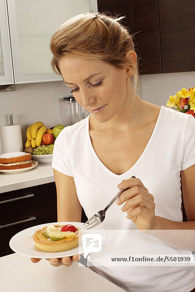 Woman In Kitchen Eating Fruit Pastry / Torte