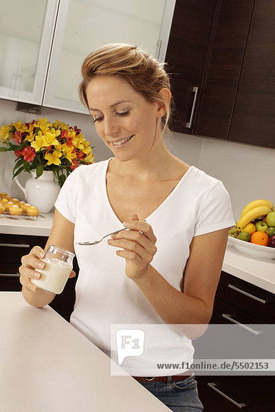 Woman In Kitchen Eating Joghurt