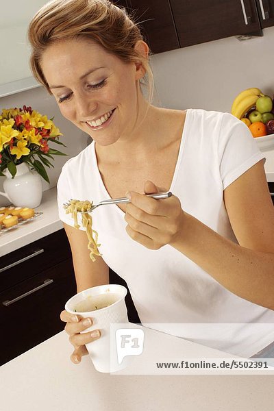 Woman In Kitchen Eating Pot Noodle