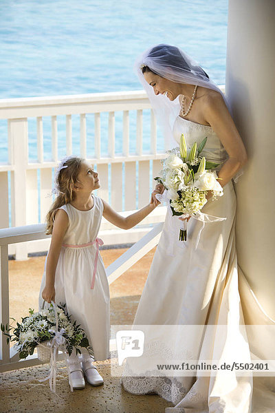 Caucasian mid-adult bride holding hands with flower girl.