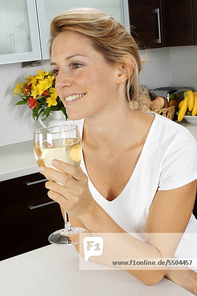 Frau In der Küche trinken Glas Weißwein