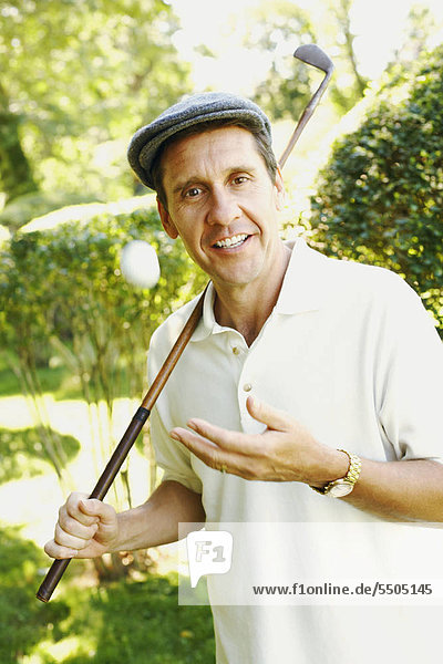 Portrait of a mature man holding a golf club and smiling