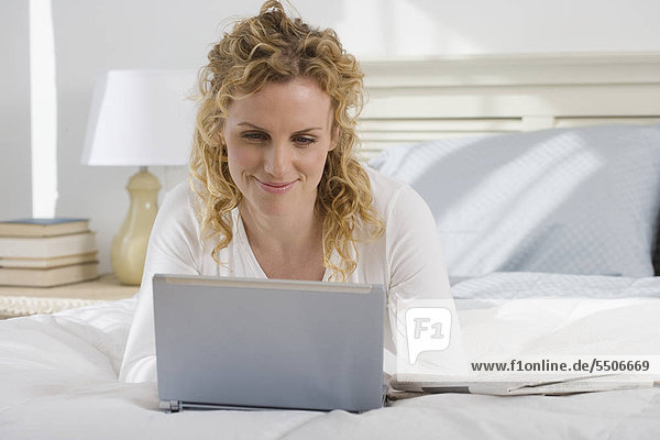 Woman looking at Laptop auf Bett