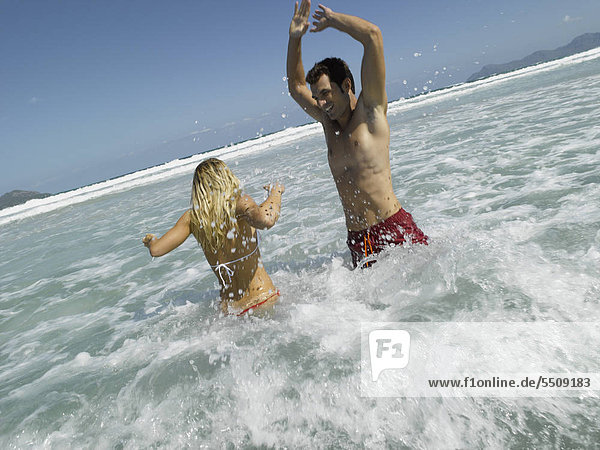 Mid adult couple splashing water in the sea