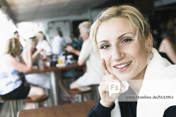 Porträt einer jungen Frau lächelnd mit der Hand auf ihr Kinn in einem restaurant