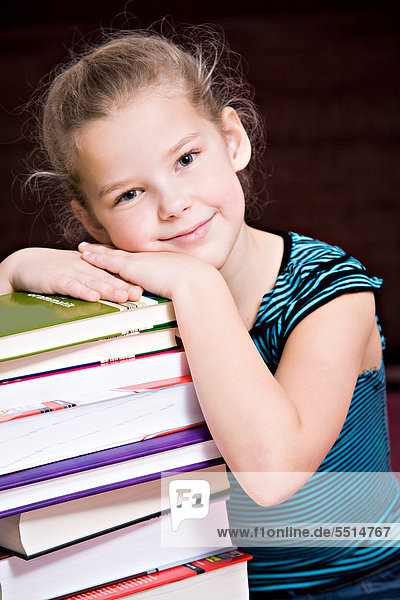 8-jähriges Mädchen mit einem Stapel Bücher
