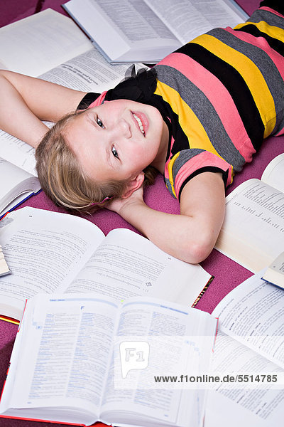 11-jähriges Mädchen liegend zwischen Büchern