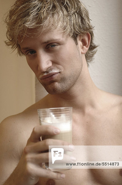 Junger Mann mit Latte Macchiato in der Hand