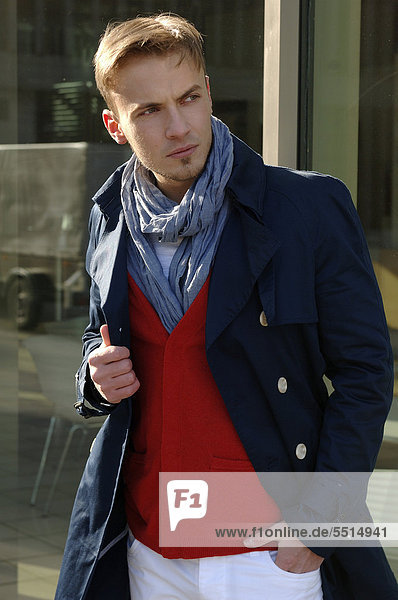 Modeaufnahme  junger Mann in blauem Mantel und rotem Pulli